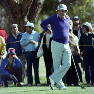 Golfer mid-swing on lush green course.