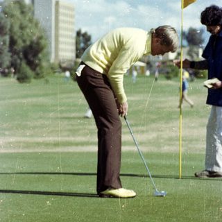 Golfer preparing to putt on green.