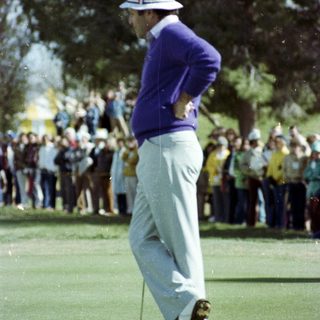 Golfer mid-swing on lush green course.