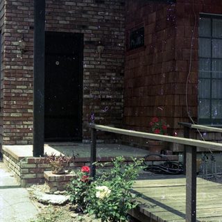 Small brick building with ramp, potted plants, and outdoor seating.