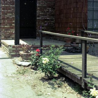 Small brick building with ramp, potted plants, and outdoor seating.