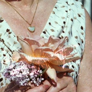 Elderly woman smiling outdoors holding a pastry.