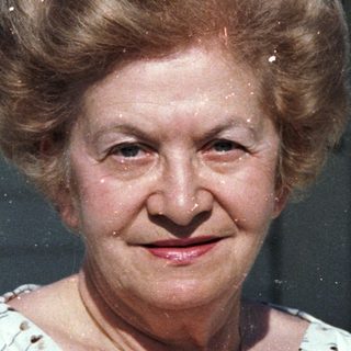 Two elderly people posing outdoors, smiling.