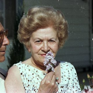 Elderly couple smiling indoors with flowers.