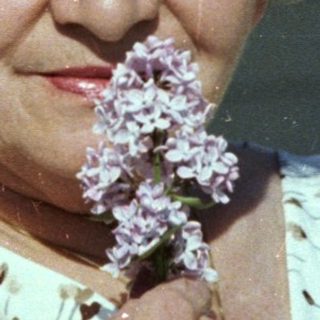Elderly couple smiling indoors with flowers.
