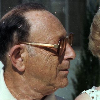 Elderly couple smiling indoors with flowers.