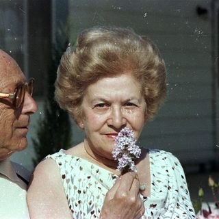 Elderly couple smiling indoors with flowers.