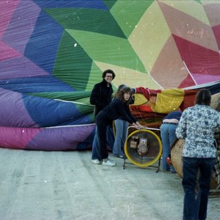 People preparing colorful hot air balloon.