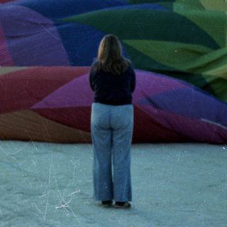Two people near a large, colorful beach balloon.