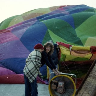 People preparing colorful hot air balloon for launch.