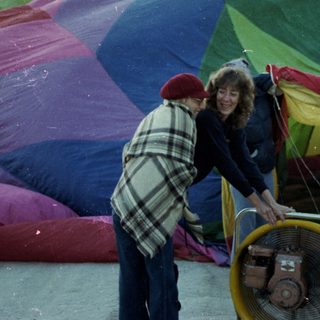 People preparing colorful hot air balloon for launch.