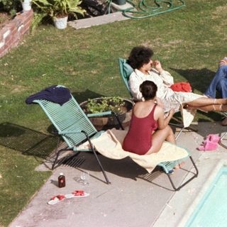 People relaxing by a backyard pool.