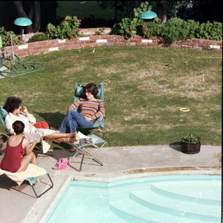 People relaxing by a backyard pool.