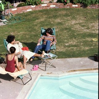 Family relaxing by a poolside on sunny day.