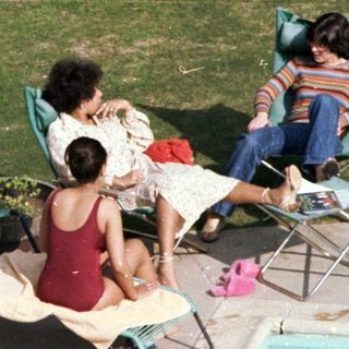 Family relaxing by a poolside on sunny day.
