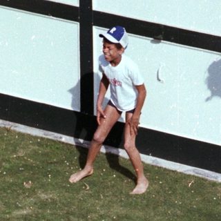 Two children playing outside with water on grass.