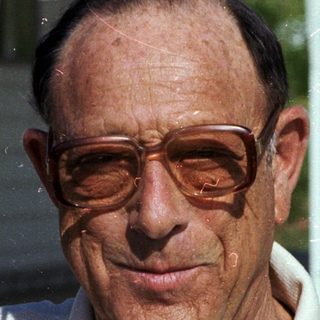Smiling older man wearing glasses outdoors.