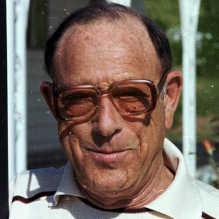 Smiling older man wearing glasses outdoors.