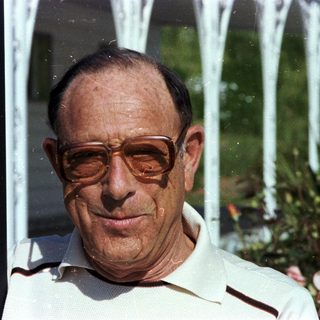 Smiling older man wearing glasses outdoors.