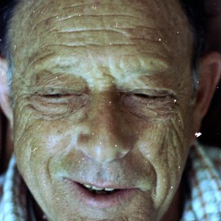 Wet, smiling elderly man with closed eyes.