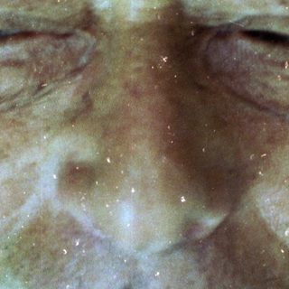 Wet, smiling elderly man with closed eyes.
