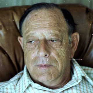 A man sitting with a thoughtful, serious expression.