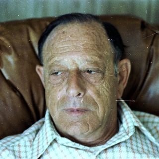 A man sitting with a thoughtful, serious expression.