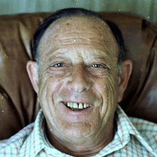 Smiling older man in plaid shirt.