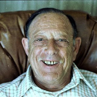 Smiling older man in plaid shirt.
