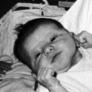 Nurse holding newborns in hospital nursery.