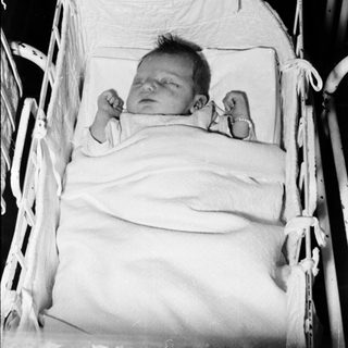 Newborn baby sleeping in hospital bassinet.