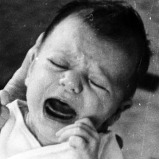 Newborn crying while being held.