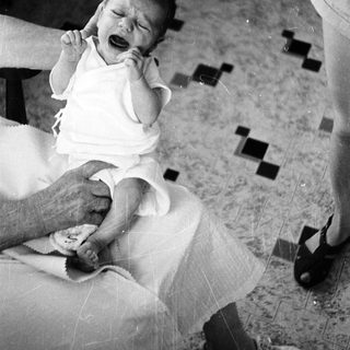 Newborn crying while being held.