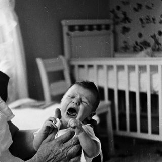 A baby crying while being held by an adult.