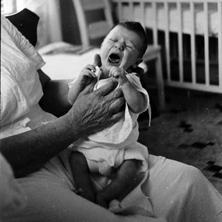 A baby crying while being held by an adult.