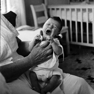 A baby crying while being held by an adult.