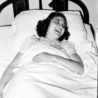 Woman smiling while lying in hospital bed.