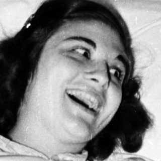 Woman smiling while lying in hospital bed.