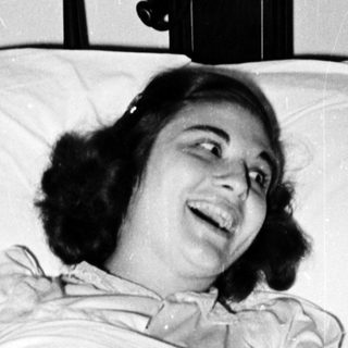 Woman smiling while lying in hospital bed.