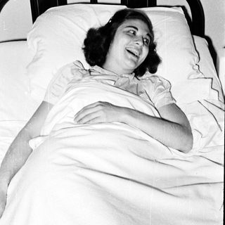 Woman smiling while lying in hospital bed.