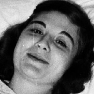 Woman lying in hospital bed, mid-20th century.