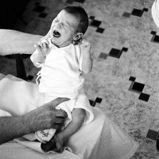 Baby crying while being held by adult.