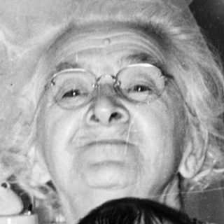 Old woman holding a baby indoors.