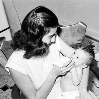 Nurse feeding infant with bottle in hospital setting.