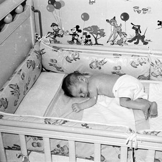Baby sleeping in Mickey Mouse-themed crib.