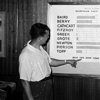 Man pointing to month-to-date aluminum sheet sales chart.