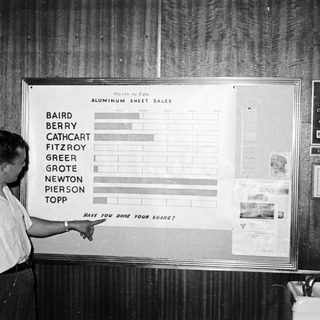 Man pointing to month-to-date aluminum sheet sales chart.