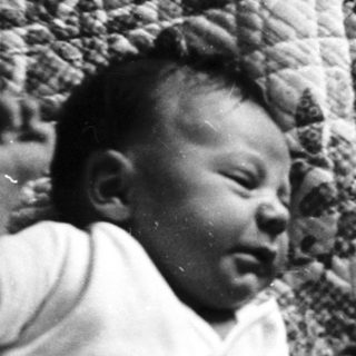 Baby crying in a crib with patterned fabric.