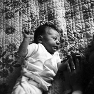 Baby crying in a crib with patterned fabric.