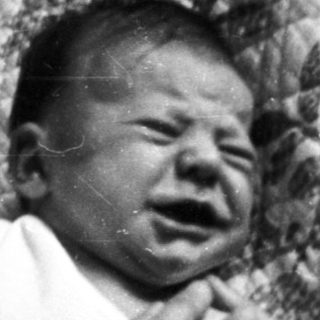 A crying infant in distressed indoor setting.
